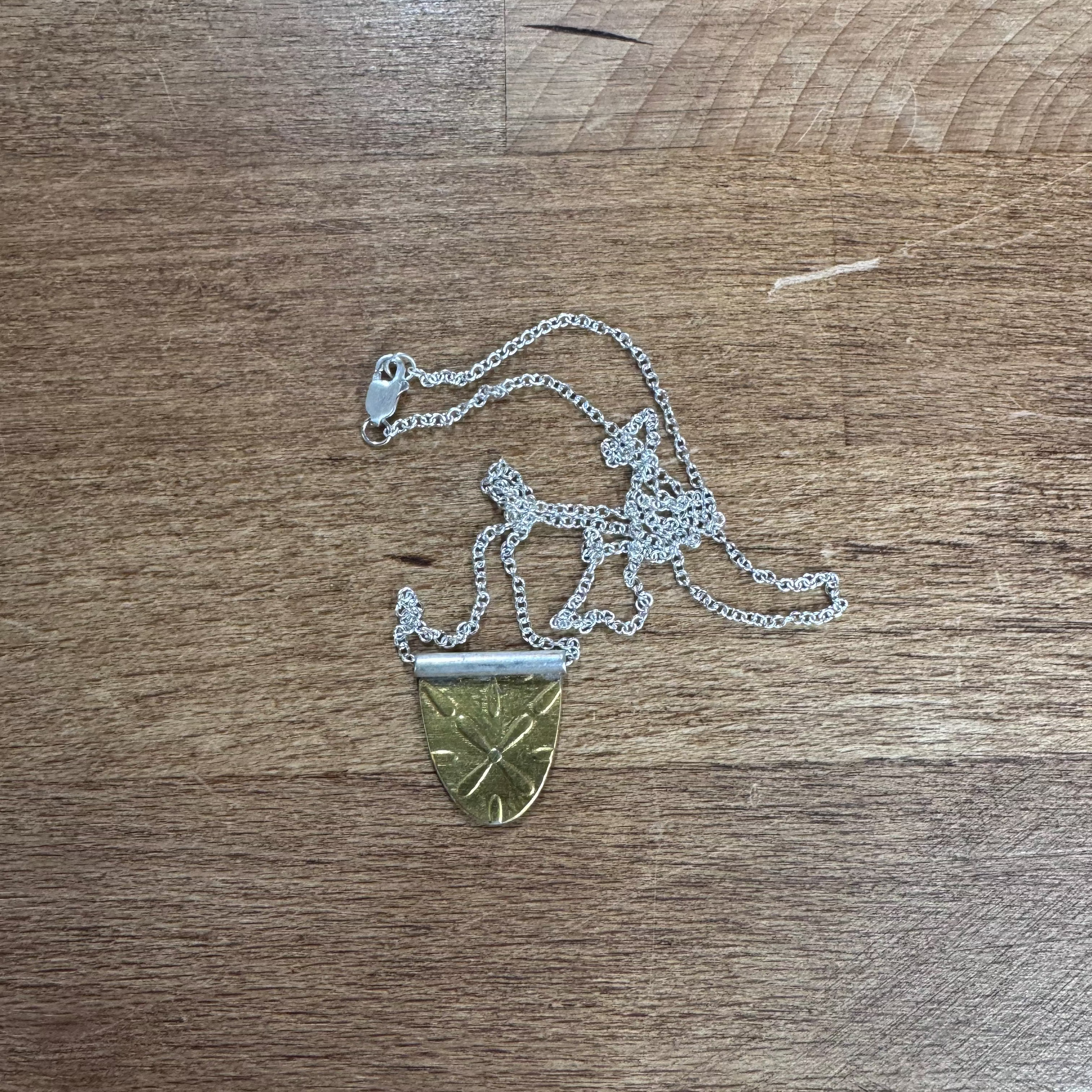 Silver necklace with a gold shield pendant